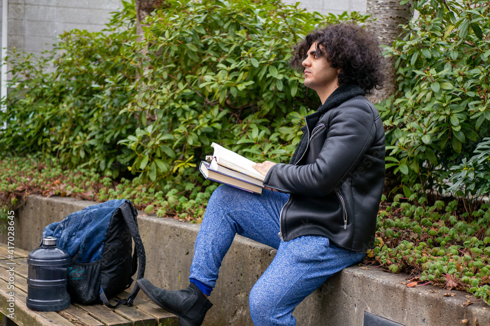 木の近くで本を読んでいる男・大学生 木の近くで本を読んでいる男・大学生