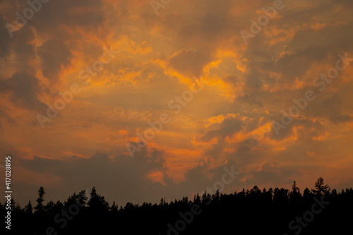 Canvas Print Smokey sunset in the mountains of orange and purple clouds in the sky with silho