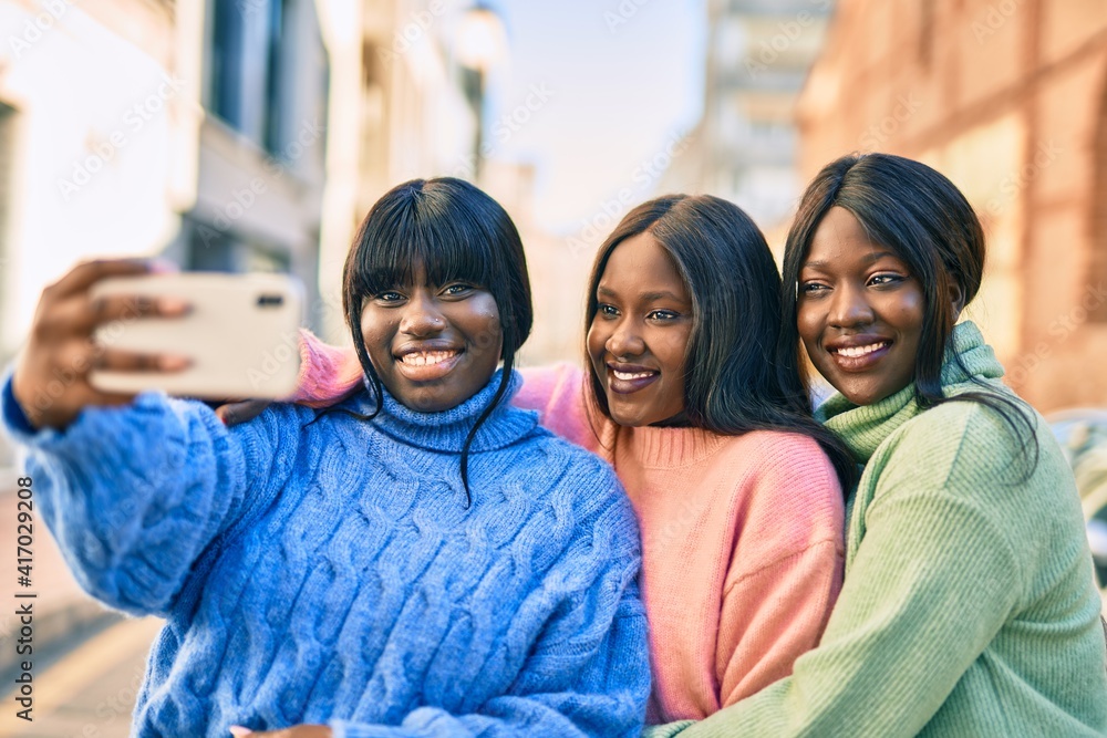 Obraz premium Three african american friends smiling happy making selfie by the smartphone at the city.