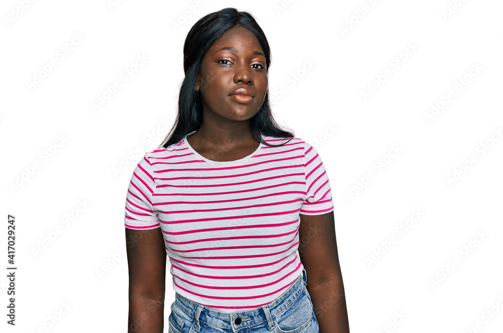 African young woman wearing casual striped t shirt relaxed with serious expression on face. simple and natural looking at the camera. African young woman wearing casual striped t shirt relaxed with serious expression on face. simple and natural looking at the camera.
