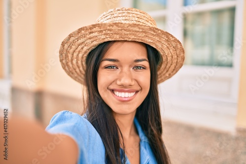 Young latin tourist girl on vacation smiling happy making selfie by the camera at the city. © Krakenimages.com