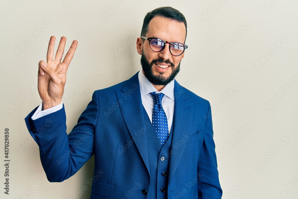 Young man with beard wearing business suit and tie showing and pointing up with fingers number three while smiling confident and happy. Young man with beard wearing business suit and tie showing and pointing up with fingers number three while smiling confident and happy.