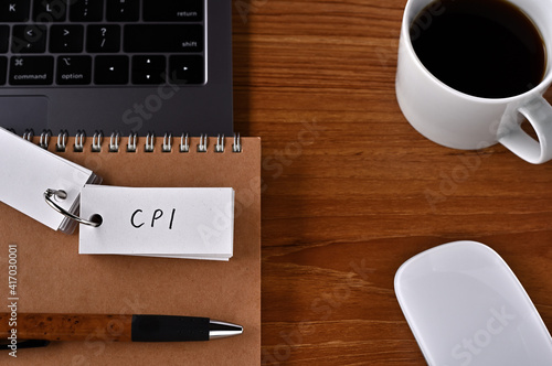 On the desk there is a laptop  a cup of coffee  and a word book with the word CPI written on it. It was an abbreviation for the financial term consumer price index.