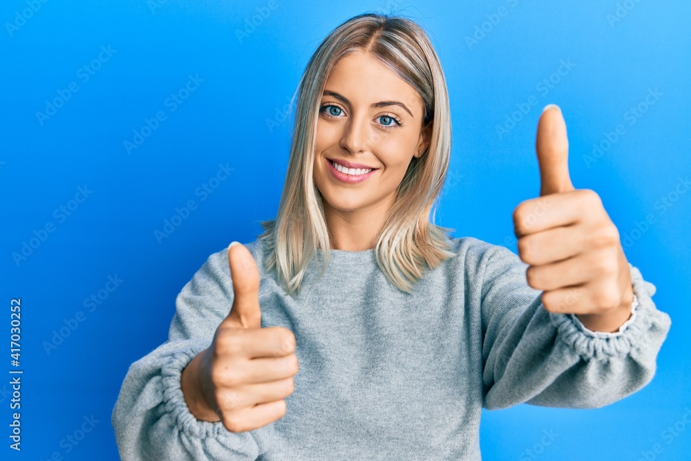 Beautiful blonde woman wearing casual clothes approving doing positive gesture with hand, thumbs up smiling and happy for success. winner gesture. Beautiful blonde woman wearing casual clothes approving doing positive gesture with hand, thumbs up smiling and happy for success. winner gesture.