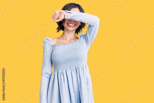 Young beautiful girl wearing casual clothes covering eyes with arm smiling cheerful and funny. blind concept.
