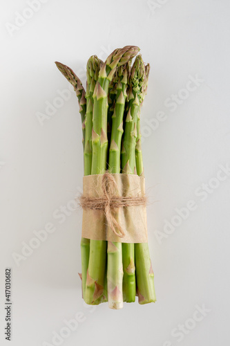A bundle of fresh green asparagus on a white background, copy space, vertical