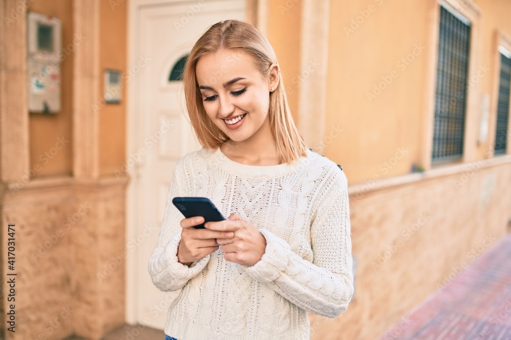 Young blonde girl smiling happy using smartphone at the city. Young blonde girl smiling happy using smartphone at the city.