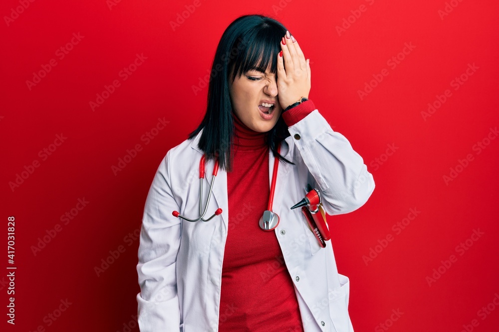 Young hispanic woman wearing doctor uniform and stethoscope yawning tired covering half face, eye and mouth with hand. face hurts in pain. Young hispanic woman wearing doctor uniform and stethoscope yawning tired covering half face, eye and mouth with hand. face hurts in pain.
