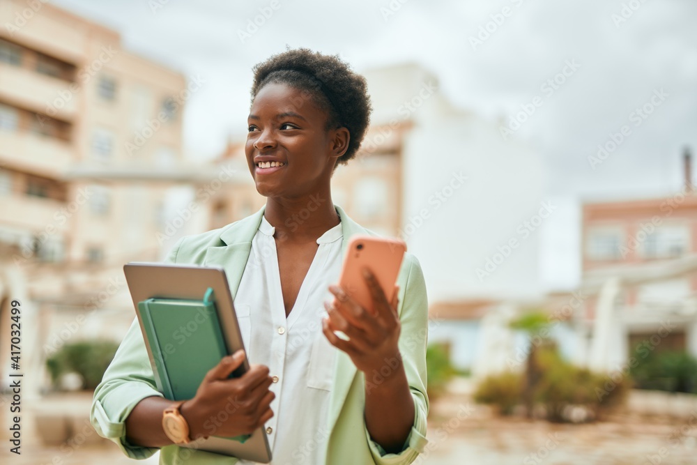 Young african american businesswoman smiling happy using smartphone at the city. Young african american businesswoman smiling happy using smartphone at the city.