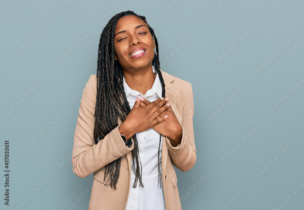 African american woman wearing business jacket smiling with hands on chest with closed eyes and grateful gesture on face. health concept. African american woman wearing business jacket smiling with hands on chest with closed eyes and grateful gesture on face. health concept.
