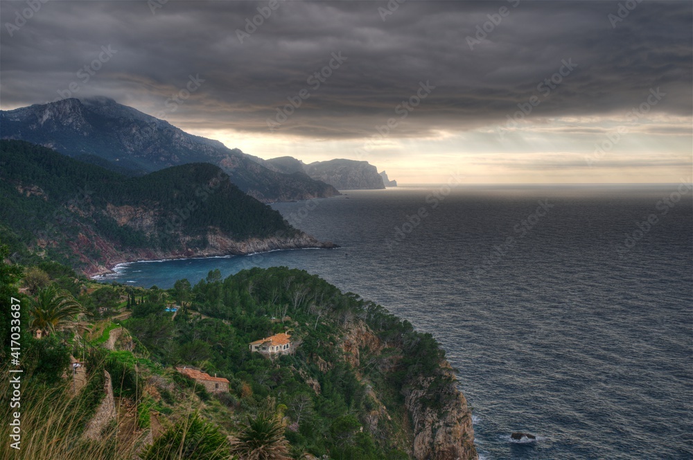 View From The Viewpoint Torre Des Verger To The Mountainous Coastline Of The Tramuntana Mountains On Balearic Island Mallorca On An Overcast Winter Day With Sunshine In The Far Distance