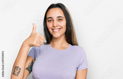 Wallpaper Mural Young hispanic woman wearing casual clothes smiling happy and positive, thumb up doing excellent and approval sign Torontodigital.ca