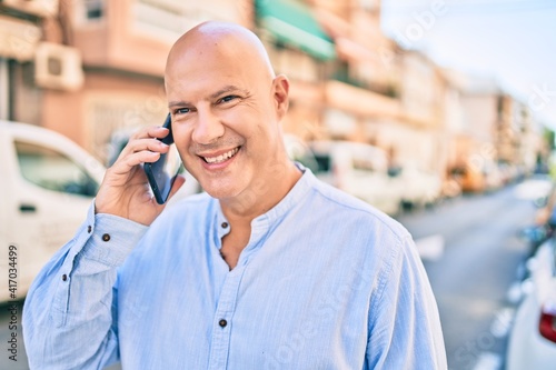 Middle age bald man smiling happy talking on the smartphone at the city.