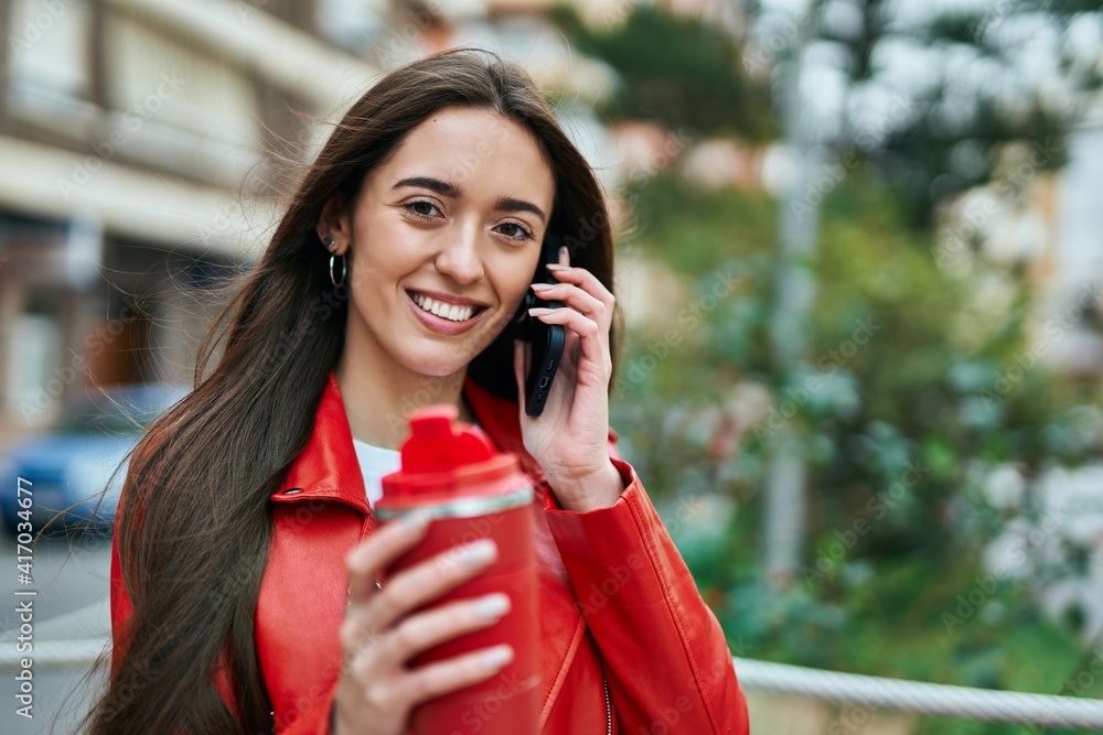 Young hispanic woman talking on the smartphone and drinking coffee at the city. Young hispanic woman talking on the smartphone and drinking coffee at the city.