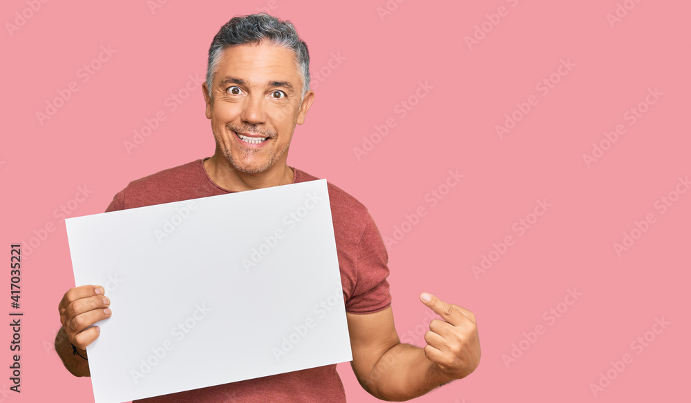 Handsome middle age man holding blank empty banner smiling happy pointing with hand and finger Handsome middle age man holding blank empty banner smiling happy pointing with hand and finger