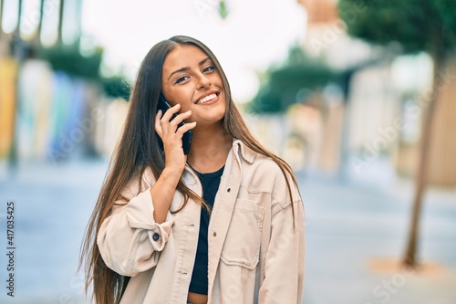 Young hispanic girl smiling happy talking on the smartphone at the city.