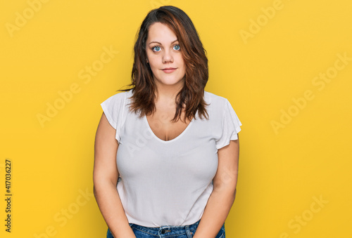 Young plus size woman wearing casual white t shirt relaxed with serious expression on face. simple and natural looking at the camera.