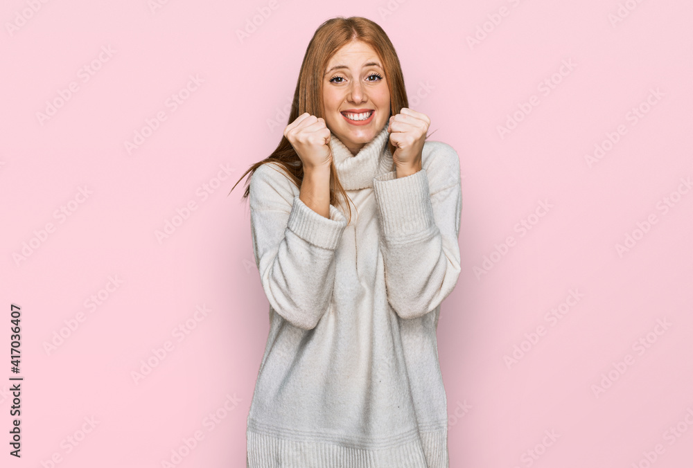 Young irish woman wearing casual winter sweater excited for success with arms raised and eyes closed celebrating victory smiling. winner concept. Young irish woman wearing casual winter sweater excited for success with arms raised and eyes closed celebrating victory smiling. winner concept.