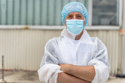 Portrait of caucasian man wearing protective mask and bouffant mob cap - Young male doctor or scientist at work in front of the laboratory hospital front view in day copy space photo