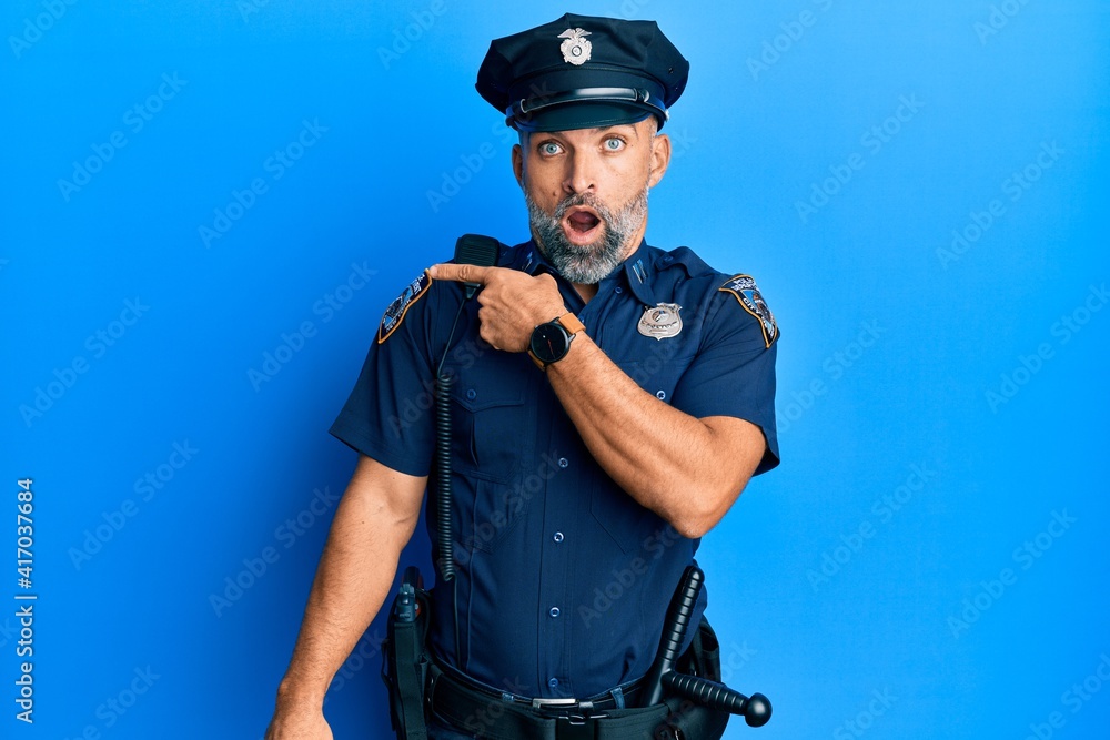 Middle age handsome man wearing police uniform surprised pointing with finger to the side, open mouth amazed expression. Middle age handsome man wearing police uniform surprised pointing with finger to the side, open mouth amazed expression.