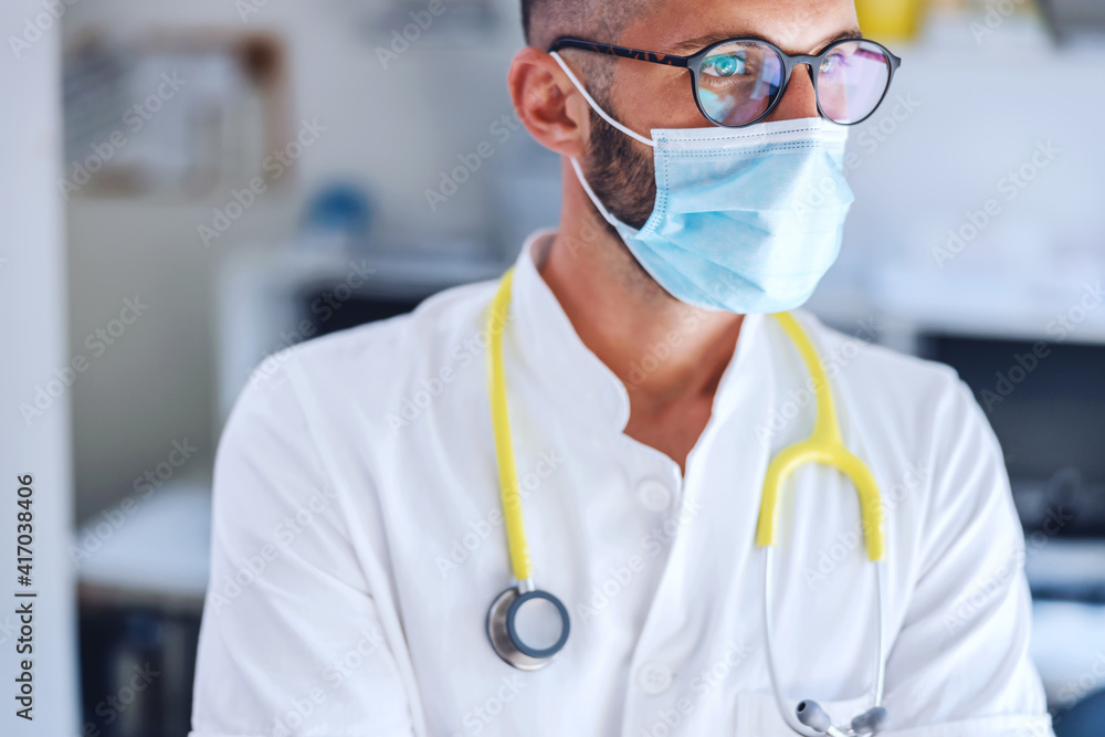 Closeup of doctor with face mask and stethoscope around his neck standing in hospital during corona virus outbreak. Closeup of doctor with face mask and stethoscope around his neck standing in hospital during corona virus outbreak.