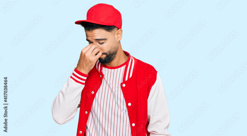 Young man with beard wearing baseball uniform tired rubbing nose and eyes feeling fatigue and headache. stress and frustration concept. Young man with beard wearing baseball uniform tired rubbing nose and eyes feeling fatigue and headache. stress and frustration concept.