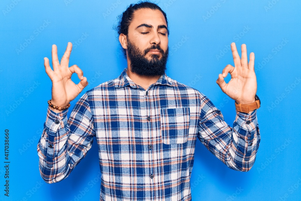 Young arab man wearing casual clothes relax and smiling with eyes closed doing meditation gesture with fingers. yoga concept. Young arab man wearing casual clothes relax and smiling with eyes closed doing meditation gesture with fingers. yoga concept.