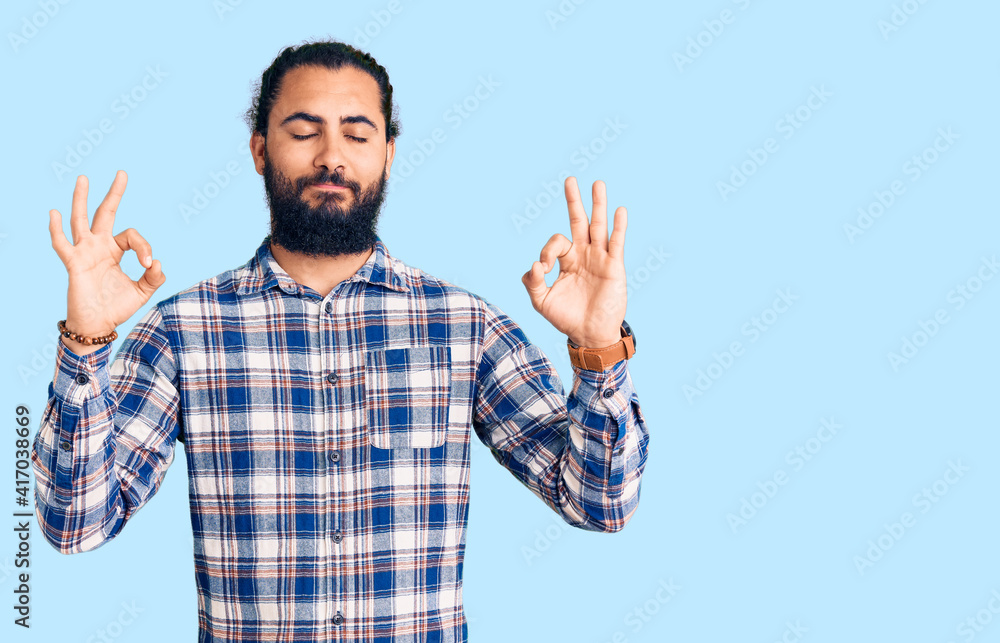Young arab man wearing casual clothes relax and smiling with eyes closed doing meditation gesture with fingers. yoga concept. Young arab man wearing casual clothes relax and smiling with eyes closed doing meditation gesture with fingers. yoga concept.