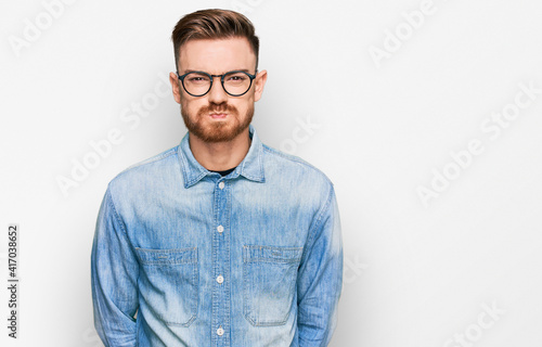 Young redhead man wearing casual denim shirt puffing cheeks with funny face. mouth inflated with air, crazy expression. © Krakenimages.com