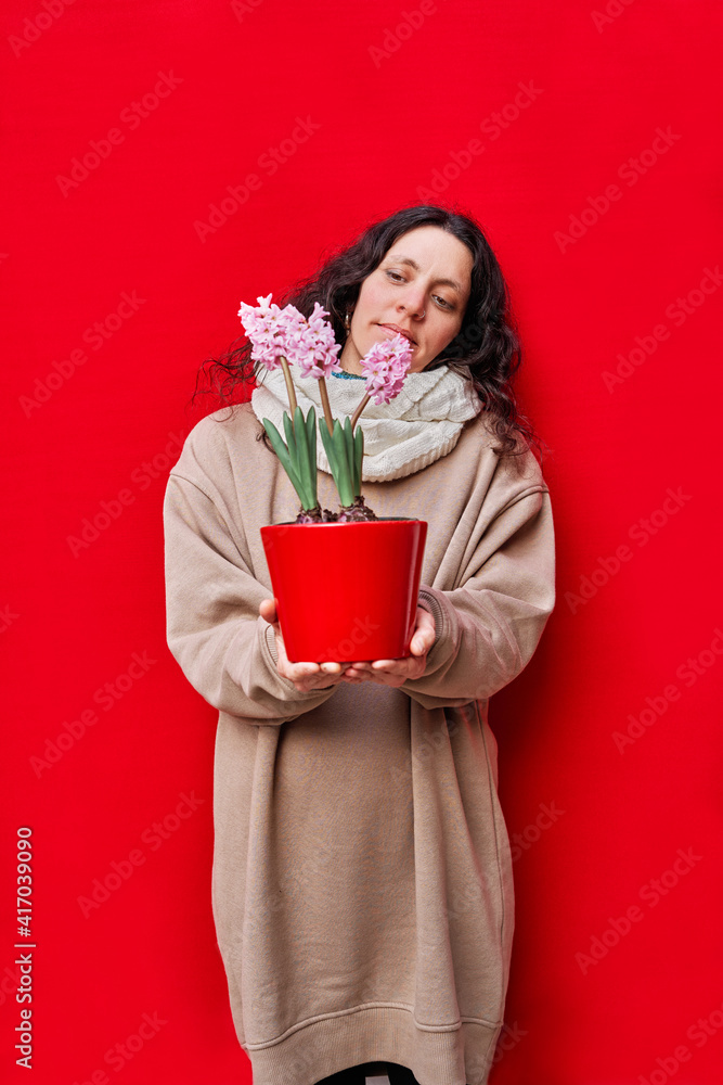 vertical photo of a beautiful woman holding a pot with hyacinth plants on red background vertical photo of a beautiful woman holding a pot with hyacinth plants on red background