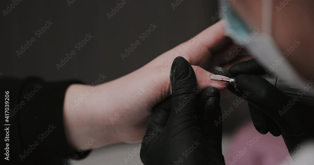 The manicurist cleans the cuticle of the nails with the device. Cuticle removal using a machine with a cutter. Professional manicure in the salon close-up. The manicurist cleans the cuticle of the nails with the device. Cuticle removal using a machine with a cutter. Professional manicure in the salon close-up.