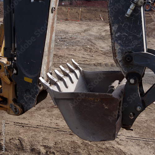 Partial view of a heavy excavator street construction machine and its hydraulic arm and bucket