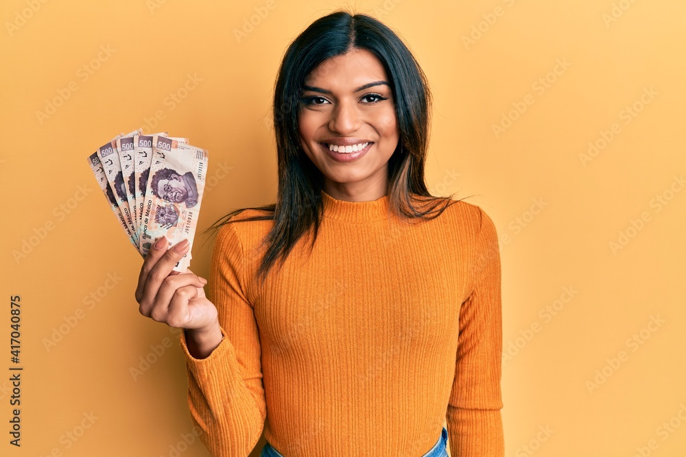 Young latin transsexual transgender woman holding 500 mexican pesos banknotes looking positive and happy standing and smiling with a confident smile showing teeth Young latin transsexual transgender woman holding 500 mexican pesos banknotes looking positive and happy standing and smiling with a confident smile showing teeth