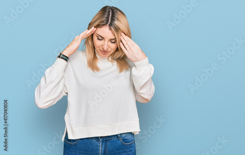 Young caucasian woman wearing casual winter sweater with hand on head, headache because stress. suffering migraine.