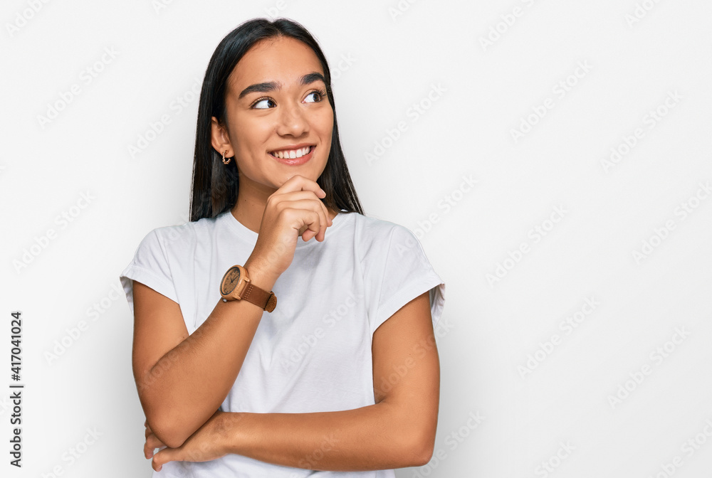 Young asian woman wearing casual white t shirt with hand on chin thinking about question, pensive expression. smiling with thoughtful face. doubt concept. Young asian woman wearing casual white t shirt with hand on chin thinking about question, pensive expression. smiling with thoughtful face. doubt concept.