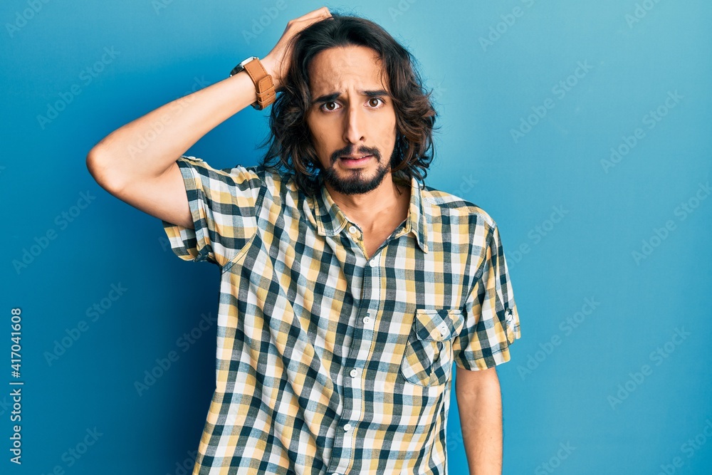 Young hispanic man wearing casual clothes confuse and wonder about question. uncertain with doubt, thinking with hand on head. pensive concept. Young hispanic man wearing casual clothes confuse and wonder about question. uncertain with doubt, thinking with hand on head. pensive concept.