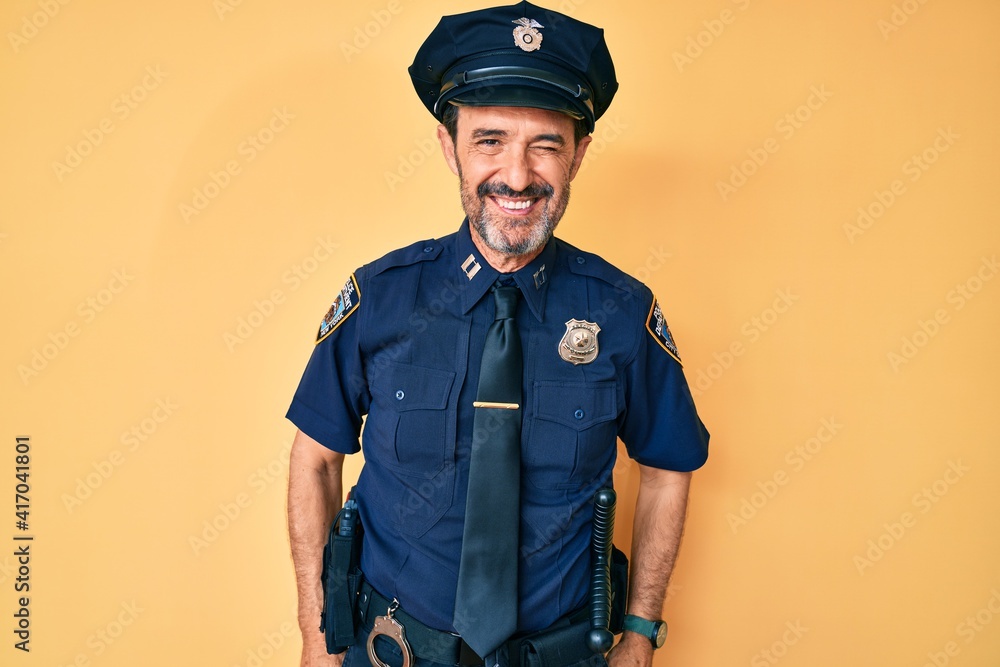 Middle age hispanic man wearing police uniform winking looking at the camera with sexy expression, cheerful and happy face. Middle age hispanic man wearing police uniform winking looking at the camera with sexy expression, cheerful and happy face.