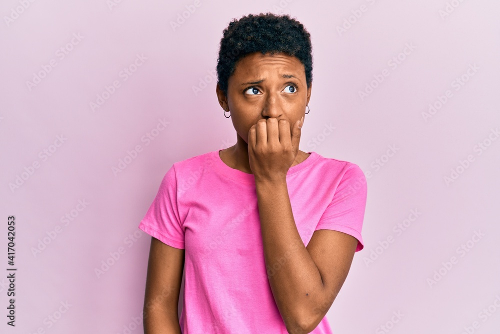 Young african american girl wearing casual clothes looking stressed and nervous with hands on mouth biting nails. anxiety problem. Young african american girl wearing casual clothes looking stressed and nervous with hands on mouth biting nails. anxiety problem.