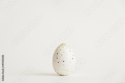 Easter white egg with glitter stars isolated on white background. Minimal easter concept. Happy Easter card with copy space for text. Top view, flatlay. Concept for banner, flyer, invitation, greeting