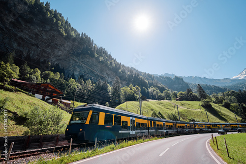 Yellow-green train running through the Swiss Alps.