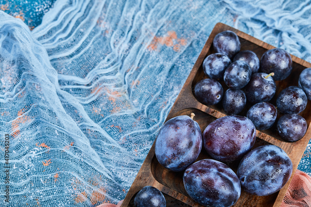 Fototapeta premium Garden plums on wooden platter with tablecloth
