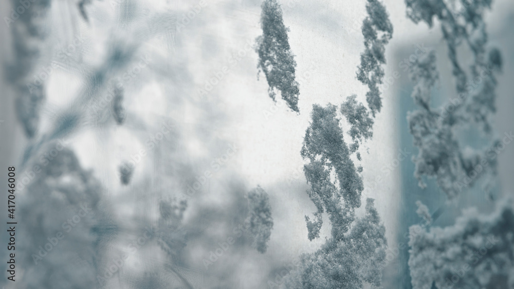 Frostwork. Decorative crystals of ice and snow on the window against the background of the city and sky. Frosty pattern. Ice texture. Frozen water. Winter background Frostwork. Decorative crystals of ice and snow on the window against the background of the city and sky. Frosty pattern. Ice texture. Frozen water. Winter background