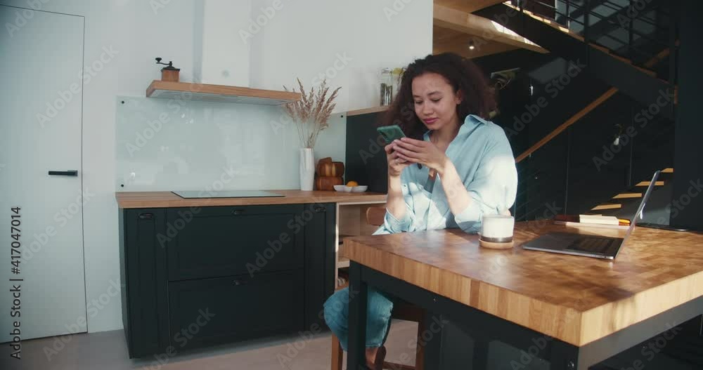 Blogging as creative occupation. Beautiful happy young mixed race student woman using smart phone at home, sips coffee. Blogging as creative occupation. Beautiful happy young mixed race student woman using smart phone at home, sips coffee.