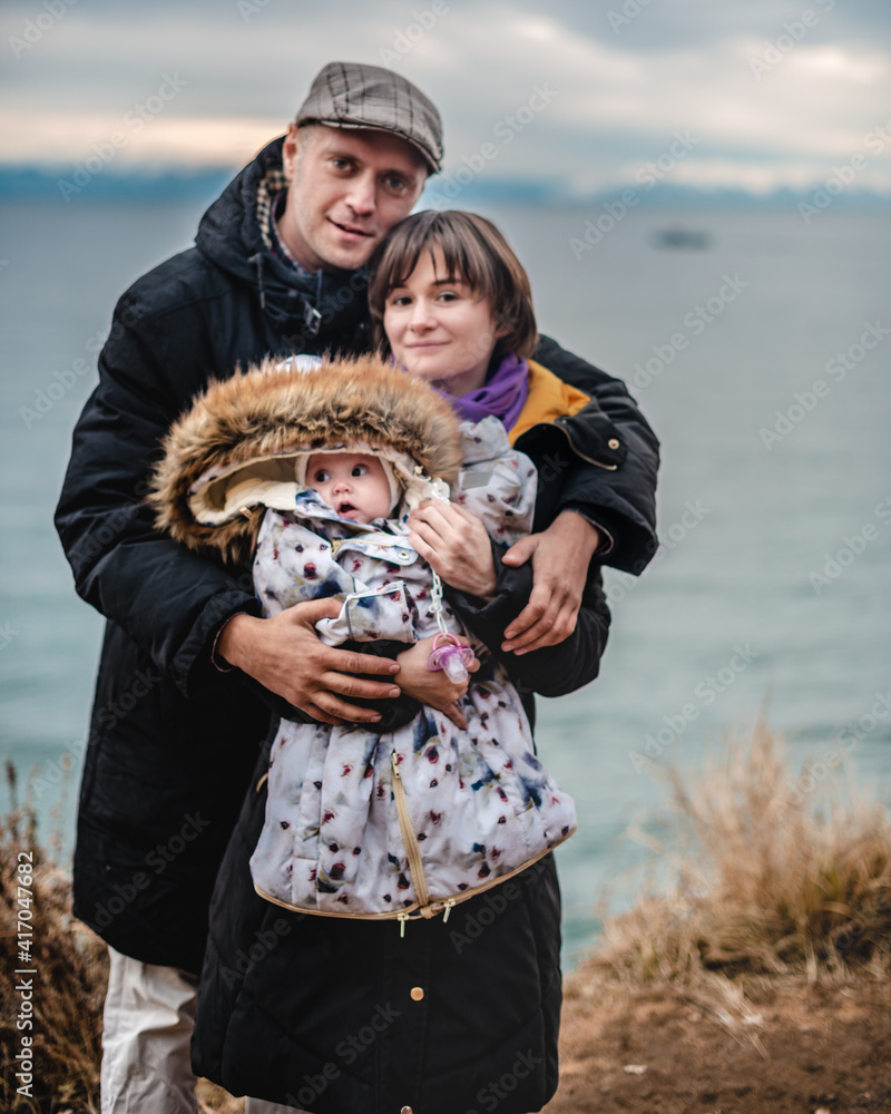 Φωτογραφία happy family with a baby in their arms, against the background of an autumn lake