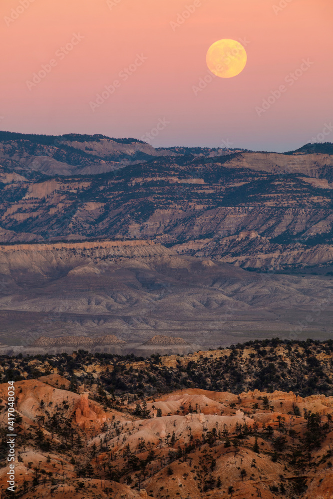 dramatic sunset with the harvest full moon in view in Bryce Canyon National Park in Utah