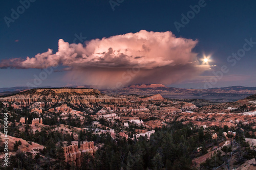 dramatic landscape photo of Bryce Canyon.gigantic cumulonimbus desert storm cloud passing through the hoodoos of the Bryce Canyon National Park just right after sunset.