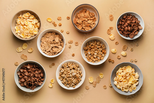 Bowls with different tasty cereals on color background