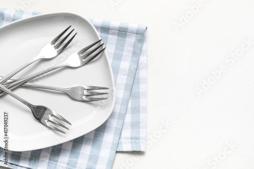 Stylish forks and plate on white background