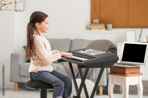 Little girl studying music with her friend online at home