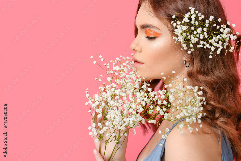 Naklejka premium Portrait of beautiful young woman with creative makeup and flowers on color background
